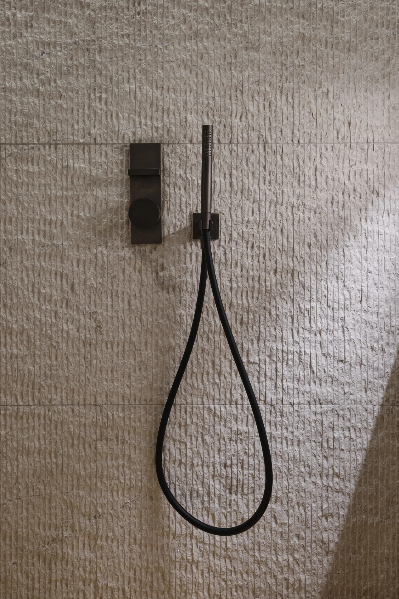 PLAYA shower set against a stone wall in soft light