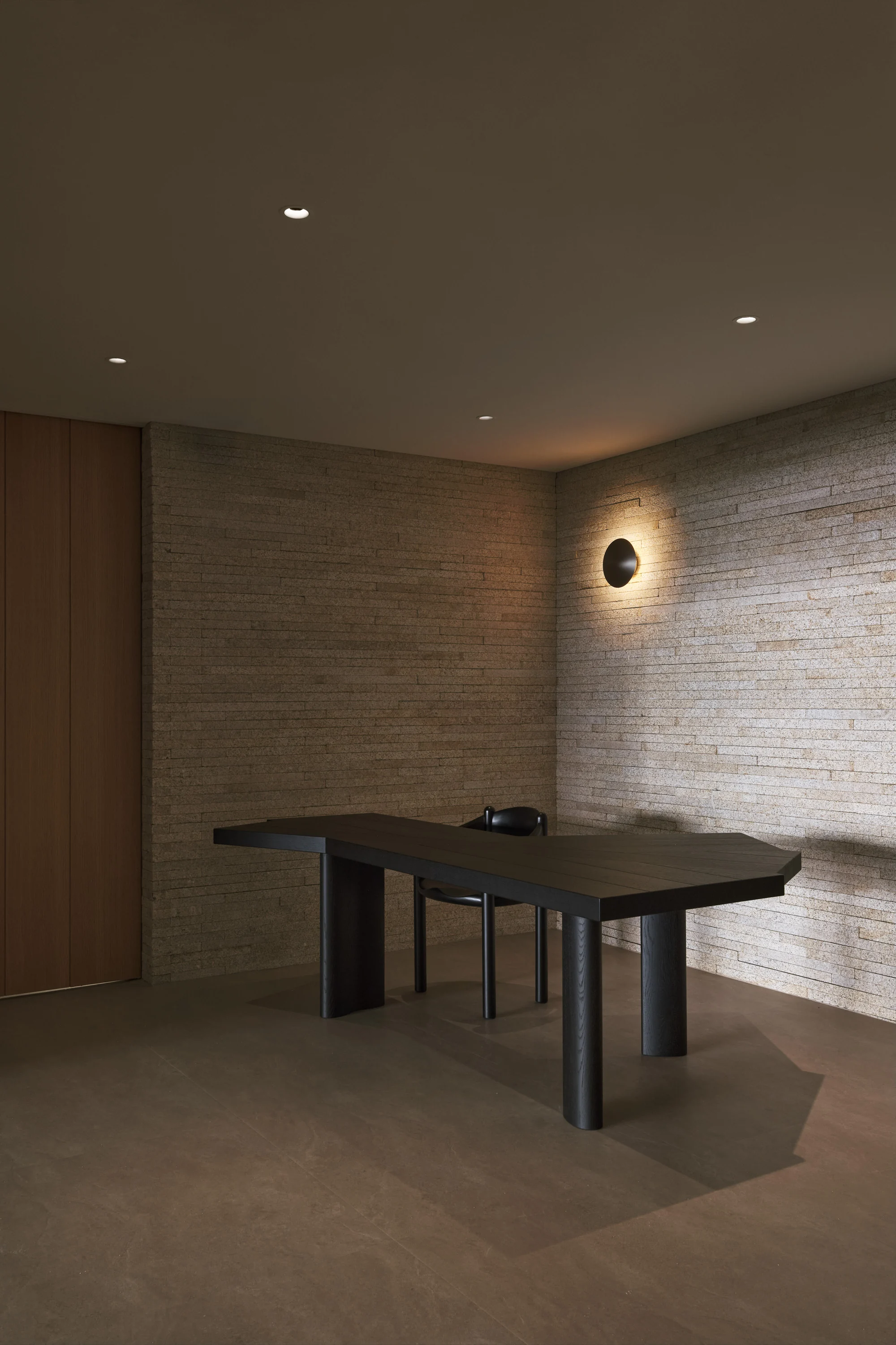 PLAYA interior with a long table, textured stone walls and warm architectural light
